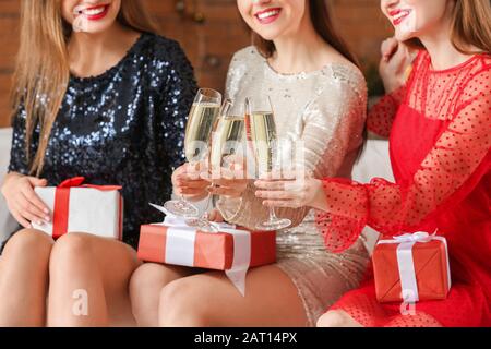 Belle giovani donne con regali di Natale e champagne a casa Foto Stock