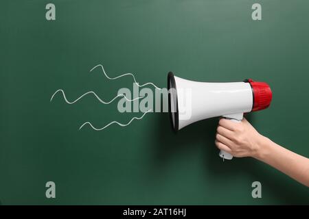 Mano femminile con megafono su sfondo a colori Foto Stock