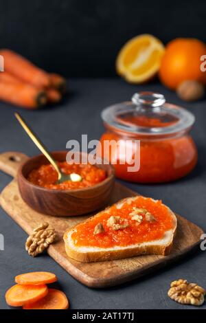 Marmellata di carote con pane e vaso su sfondo scuro. Orientamento verticale Foto Stock