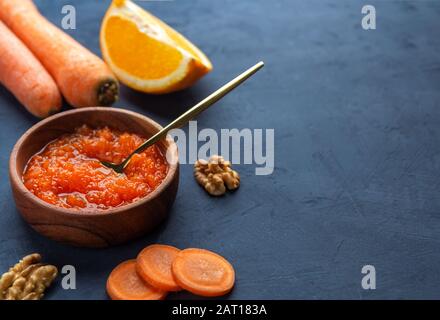 Marmellata di carote vegetali in una ciotola di legno su uno sfondo blu scuro, un luogo per il testo. Orientamento orizzontale Foto Stock