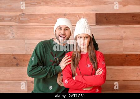 Ritratto di coppia emotiva in abiti di Natale su sfondo di legno Foto Stock