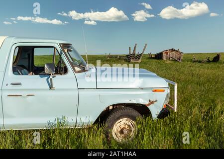 Camion blu in un campo aperto con vecchio capannone rundown e sfondo blu cielo nube Foto Stock