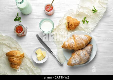 Gustosi croissant con burro e latte su tavola bianca Foto Stock