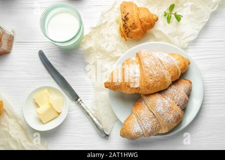 Gustosi croissant con burro e latte su tavola bianca Foto Stock