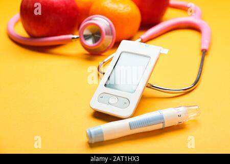 Glucometro digitale, penna lancet, stetoscopio e frutta su sfondo colorato. Concetto di diabete Foto Stock