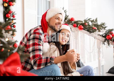 Coppia felice bere tè in veranda decorato per Natale Foto Stock