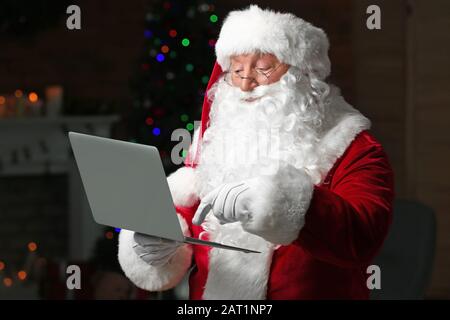 Babbo Natale con il computer portatile in camera decorata per Natale Foto Stock