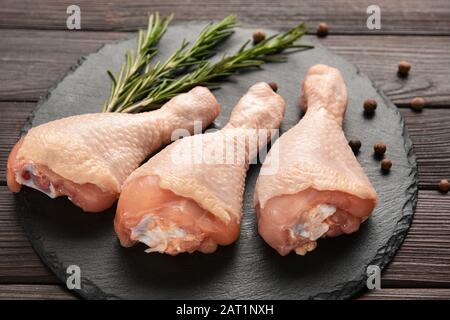 Tamburi di pollo crudi su sfondo di legno Foto Stock