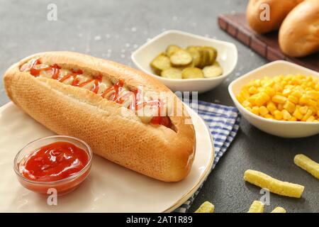 Piatto con gustoso cane caldo sul tavolo Foto Stock