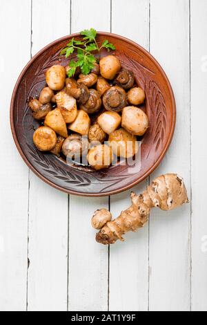 Carciofi di Gerusalemme arrosto con funghi champignon. Arrosto con patate e funghi. Cibo vegetariano. Foto Stock