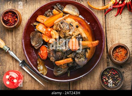 Stinco di maiale arrosto eisbein con verdure su sfondo di legno. Stanghetta di maiale brasata Foto Stock