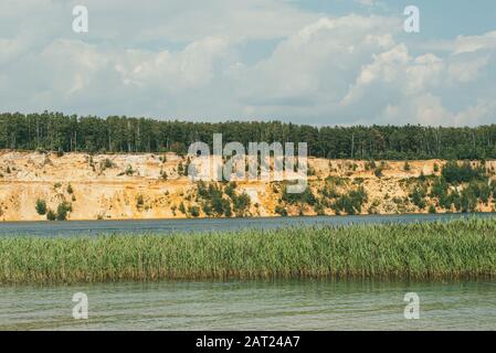Alta spiaggia rocciosa e ripida coperta di pini un lago limpido e blu Foto Stock