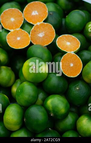 Appena raccolto green tangerini mandarini, clementine, come gli agrumi sfondo. Foto Stock