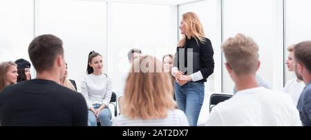 Giovane donna in piedi in cerchio dei suoi colleghi. Foto Stock