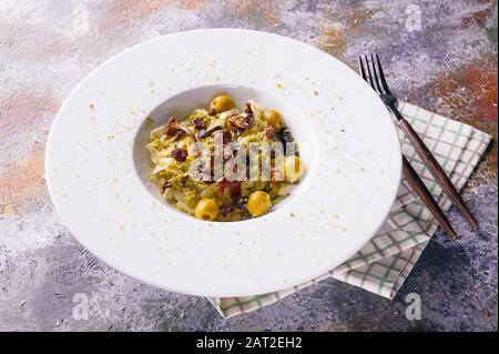 Fettuccini con funghi canterelle, olive e pesto in un piatto bianco. Cucina Italiana Mediterranea. Primo piano Foto Stock