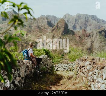 Santo Antao, Capo Verde. Donna turistica con zaino godendo arido crinale di montagna sulla strada per la valle di Coculi di Ribeira Grande Foto Stock