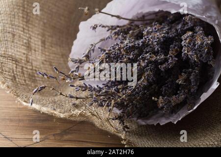 bouquet di lavanda avvolto in sacco e carta su fondo di legno Foto Stock