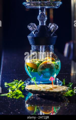 Produzione di zoccoli nell'ananas. L'ananas tagliato si trova nella ciotola della narghilè. Fiasca rotonda con cappuccio e liquido blu. Hookah sull'ananas. Foto Stock