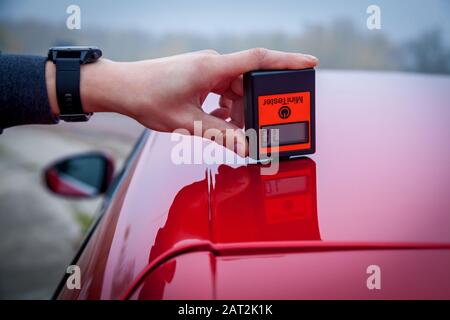 Misurare lo spessore della vettura di rivestimento di vernice di colore rosso con una vernice misuratore di spessore. Foto Stock