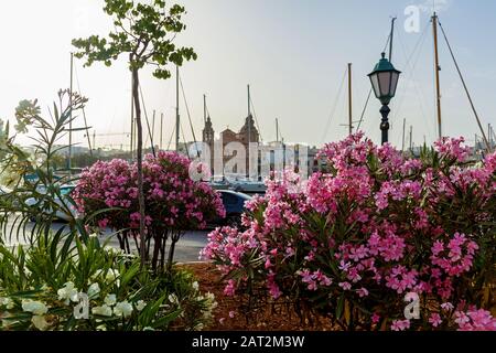 Bellissima vista della cattolica Chiesa barocca su uno sfondo di cielo blu. Incredibile paesaggio con vecchie case e le tradizionali luzzus nel porto. Foto Stock