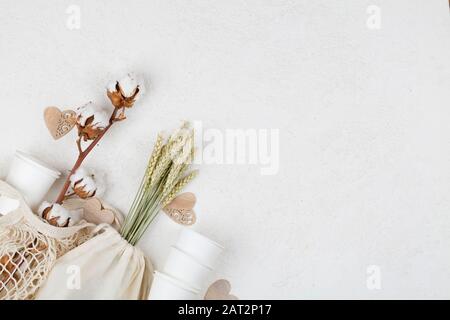 cuori di legno, fiori di cotone e tazze di carta eco naturale, borsa a corda, grano su sfondo bianco. concetto di stile di vita sostenibile. zero rifiuti, plastica fre Foto Stock