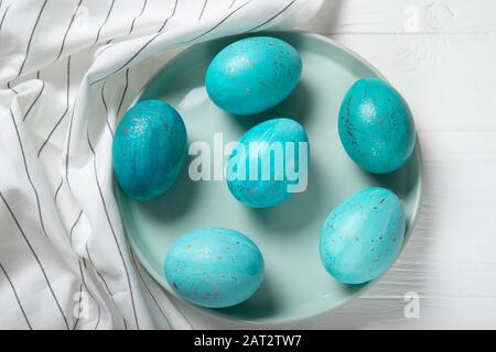 Uova di Pasqua su un piatto blu. Uova blu con spruzzi d'oro. Pasqua. Vista dall'alto Foto Stock