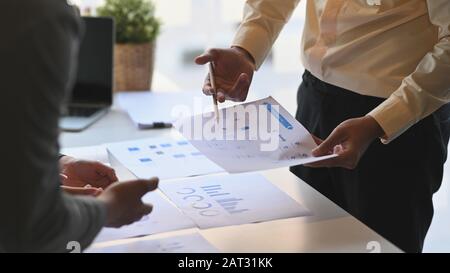 Taglio corto di giovani uomini d'affari mentre analisi di loro nuovo progetto. Concetto di discussione per le persone in viaggio di lavoro. Foto Stock