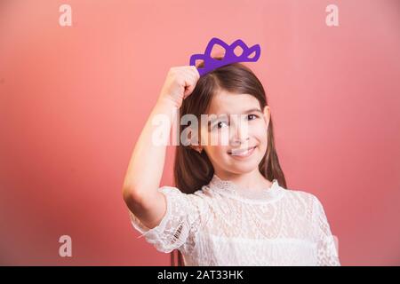 una bella ragazza in un abito bianco pone in modo giocoso su uno sfondo rosa Foto Stock