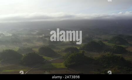 Paesaggio tropicale con terreno agricolo e verdi colline, vista aerea. La natura dell'isola di Luzon, Filippine. Nebbia la mattina presto. Foto Stock