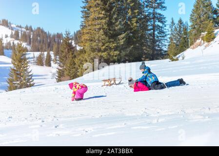 Madre che gioca con i bambini nella neve sulla montagna. Concetto di spendere tempo sulla neve e di aumentare la salute dei bambini Foto Stock