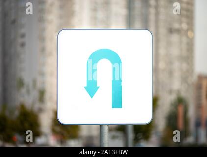 U-turn strada segno su sfondo urbano blurry Foto Stock