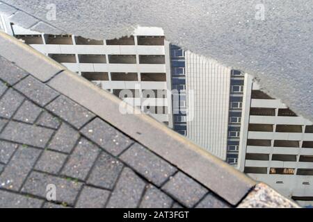 28 gennaio 2020, Sassonia-Anhalt, Magdeburg: La facciata di un alto edificio residenziale si riflette in una pozza di pioggia. Foto: Klaus-Dietmar Gabbert/dpa-Zentralbild/ZB Foto Stock