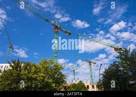 Berlino, Stato di Berlino / Germania - 2018/07/30: Vista panoramica di più gru da cantiere sui nuovi progetti di sviluppo di edifici residenziali a Berlino Est lungo il fiume Sprea Foto Stock