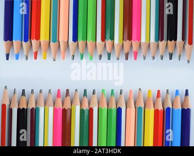 Un mazzo di pastelli di matita colorati differenti disposti insieme in due file differenti mentre sono rivolti l'uno verso l'altro Foto Stock