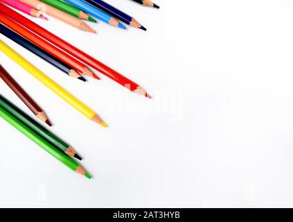 mazzo di pastelli di cera di colori diversi sono sparsi casualmente su uno sfondo bianco brillante Foto Stock