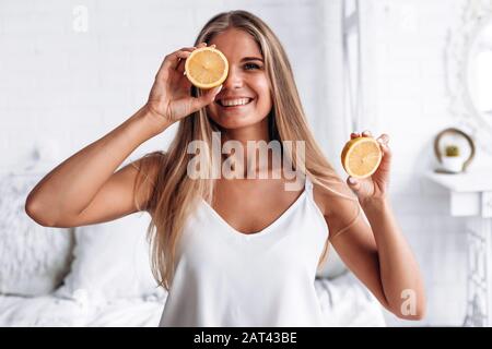 Bella ragazza bionda decide limone in mano e chiude l'occhio Foto Stock