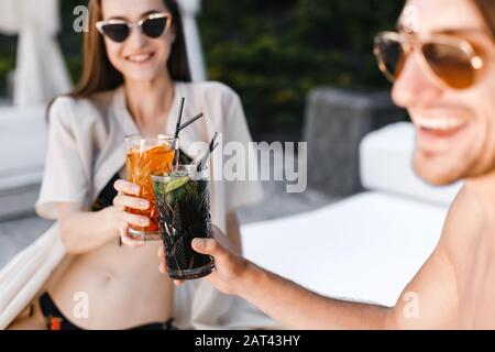 Coppia sorridente che beve cocktail a bordo piscina Foto Stock
