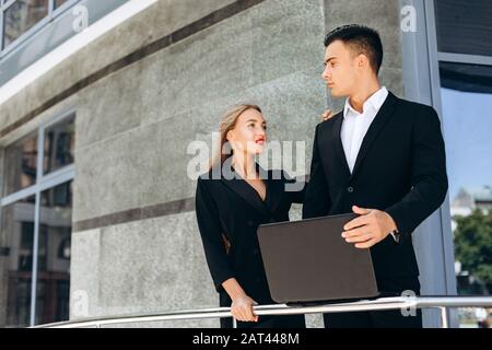 Immagine di un uomo d'affari serio e di una donna sorridente come partner commerciali Foto Stock