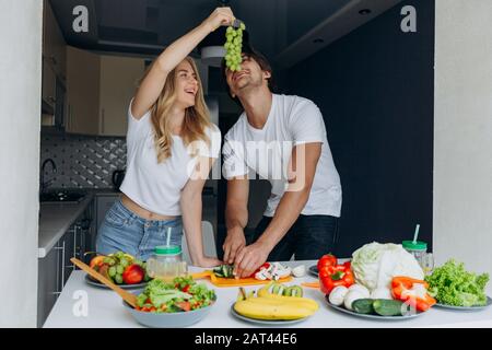Donna che alimenta un uomo con uve durante l'uomo che taglia un vegetale- immagine Foto Stock