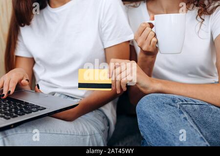 Giovane donna tenendo la carta di credito e con il computer portatile. Shopping on line concept Foto Stock