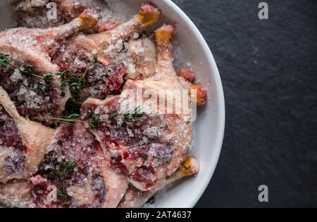 Gambe di mallard selvatiche crude che sono state lasciate marinare in sale ed erbe prima di essere cucinate. Questa è una versione fatta in casa del famoso confit d'anatra. Dor Foto Stock