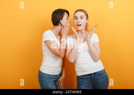 La donna dice un segreto al suo amico. Meraviglia emozione sul viso . - Immagine Foto Stock