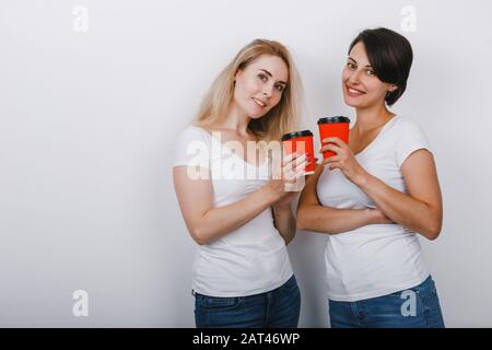Ritratto di due amici donne alzò bicchieri di caffè e guardando delicatamente la fotocamera Foto Stock