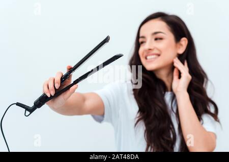 Bella, ragazza sorridente che tiene una piastra nelle sue mani. Primo piano, sfondo sfocato Foto Stock