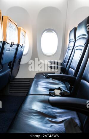 Aereo interno - cabina con moderna sedia in pelle per passeggeri di aereo. Sedili e finestre dell'aeromobile. - immagine Verticale Foto Stock