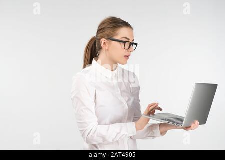 Donna in occhiali funziona su un computer portatile in piedi. Osservare attentamente lo schermo Foto Stock