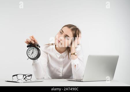 Sad donna siede accanto a un computer portatile e guarda lontano tiene sveglia e mette la testa sul suo braccio Foto Stock