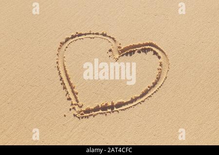 Il segno del cuore disegnato a mano è su una sabbia costiera, una metafora romantica di vacanza Foto Stock
