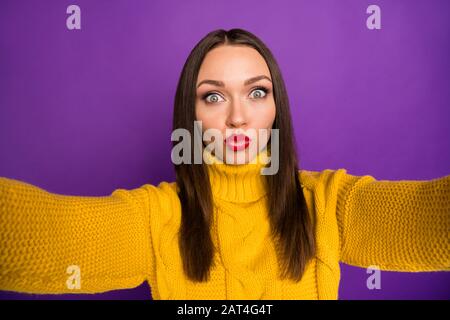 Auto primo piano foto di allegro positivo bella donna baciarti attraverso la fotocamera si sta prendendo selfie con isolato in giallo ponticello su Vivid viola Foto Stock