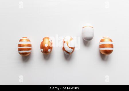 Vista dall'alto della decorazione dorata delle uova di pasqua su sfondo bianco. Composizione festiva Foto Stock